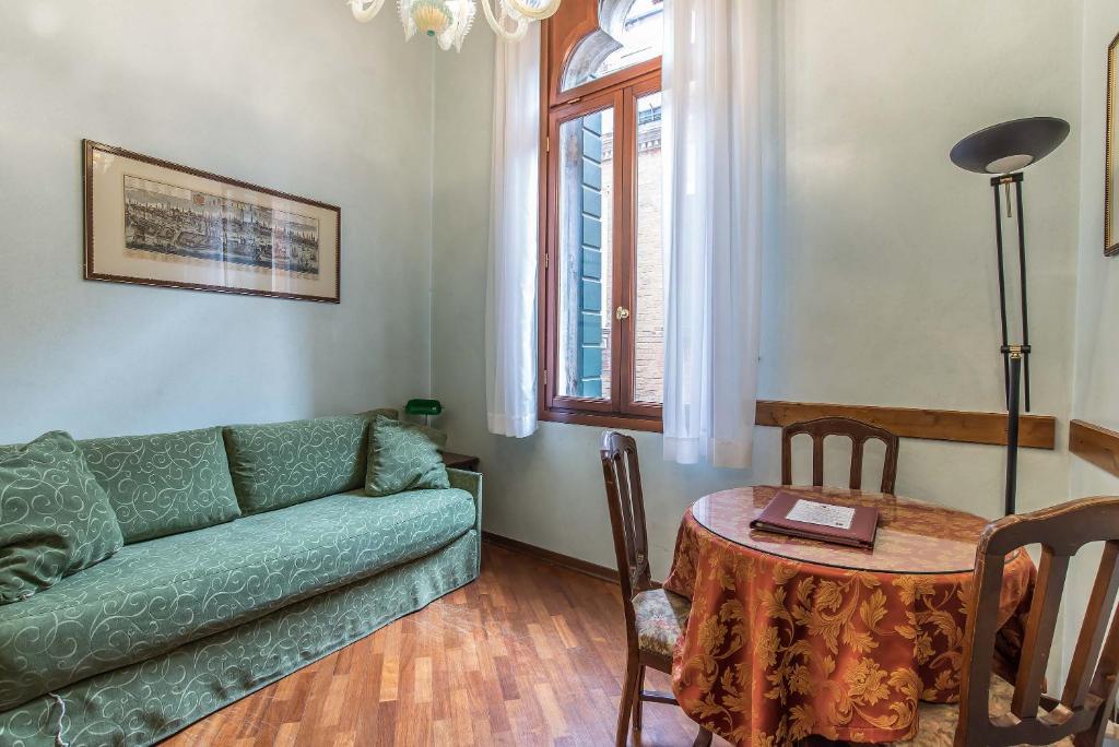 uma sala de estar com um sofá verde e uma mesa em Hotel Piccola Fenice em Veneza