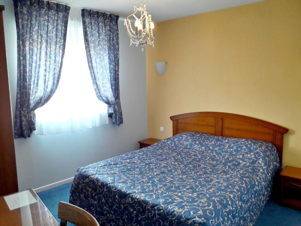 a bedroom with a blue bed and a window at Logis Hotel du Chemin des Dames in Corbeny