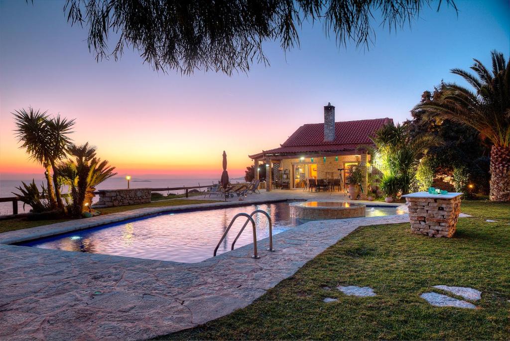 a house with a swimming pool in front of the ocean at Villa Sunrise Lagonisi in Lagonissi