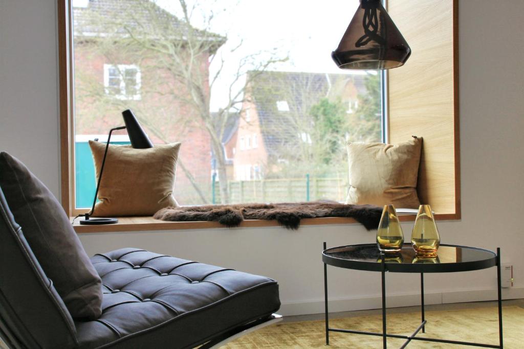 uma sala de estar com um sofá, uma mesa e uma janela em Sommerloft Norderney Ferienhaus em Norderney