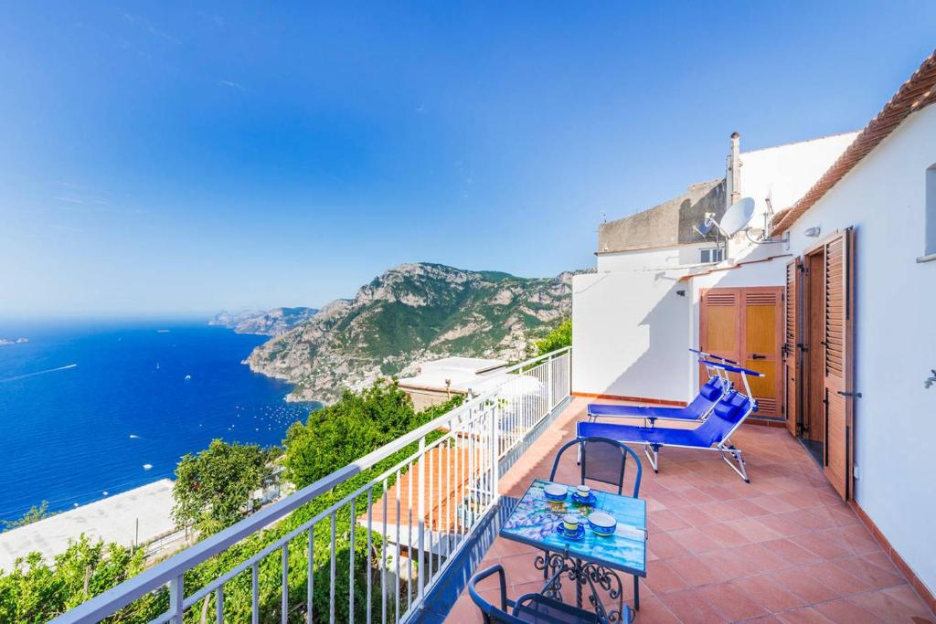 een balkon met blauwe stoelen en uitzicht op de oceaan bij Casa Satriano in Positano
