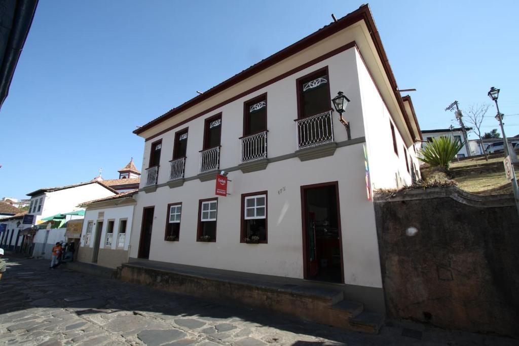 a white building with black windows on a street at Casa Antunes in Diamantina