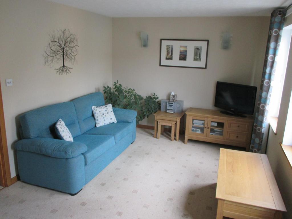 a living room with a blue couch and a tv at Apartment 76 in Kirkwall