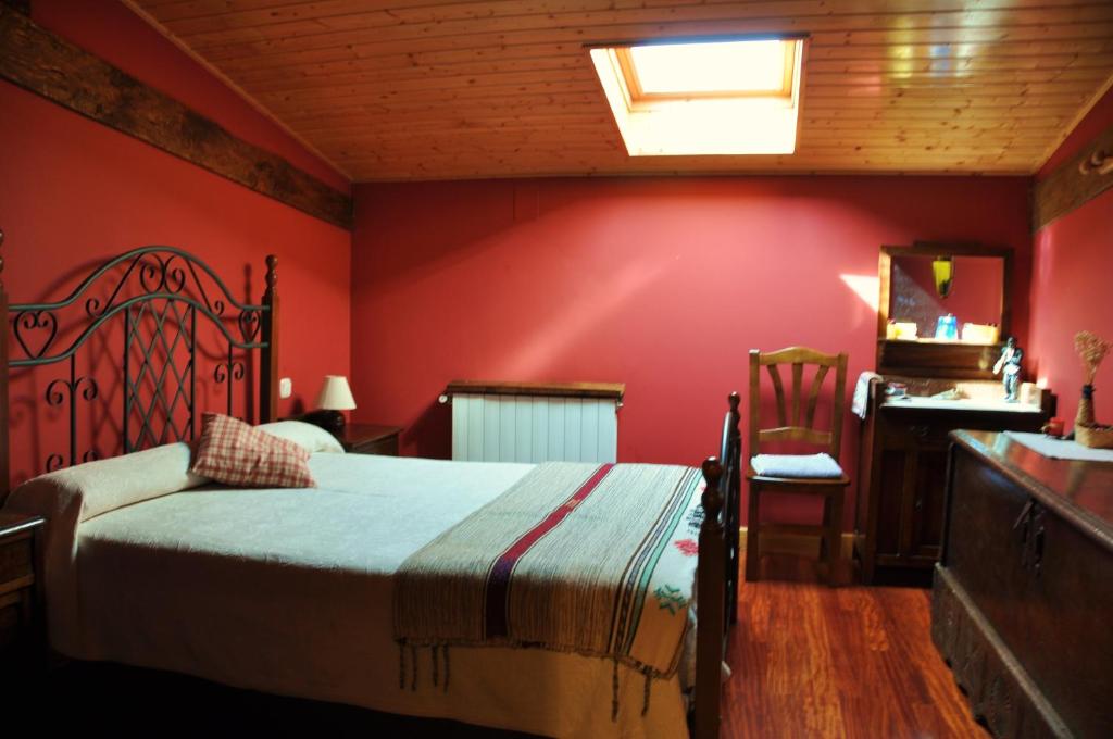 Schlafzimmer mit roten Wänden, einem Bett und einem Schreibtisch in der Unterkunft Casa Rural Altzuste Landetxea in Zeanuri