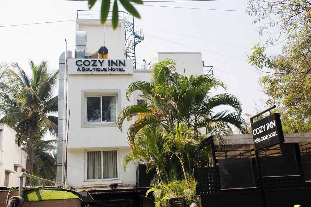 a white building with a sign that reads cozy inn apartments at Hotel Cozy Inn in Pune