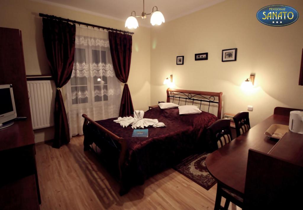 a bedroom with a bed with a table and a dining room at Pensjonat Sanato in Busko-Zdrój