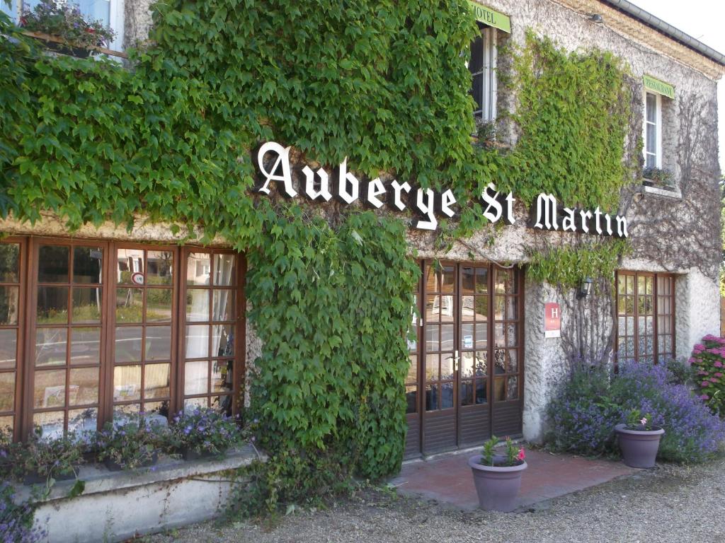un bâtiment recouvert de lierre avec un panneau indiquant antwerpes st martin dans l'établissement Logis Hôtel Restaurant Auberge Saint Martin, à Surville