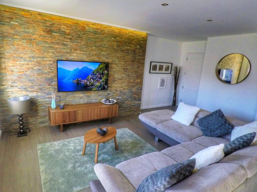 a living room with two couches and a tv on a brick wall at House Colegio de Gaia in Vila Nova de Gaia