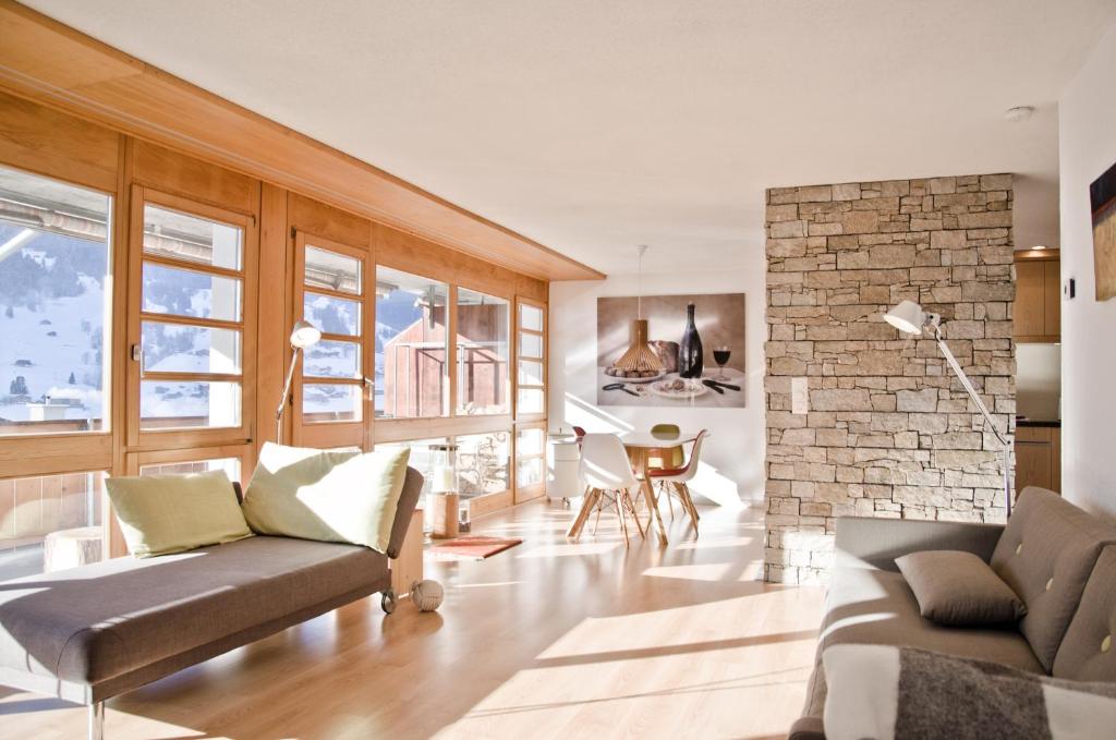 uma sala de estar com um sofá e uma lareira de pedra em Apartment Matterhorn - GRIWA RENT AG em Grindelwald