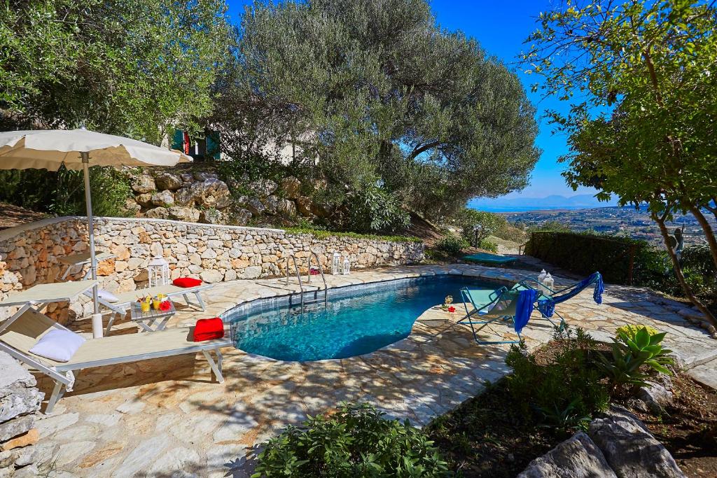 una piscina con sillas y sombrilla en Villa Del Sol - Scopello-Villas, en Scopello