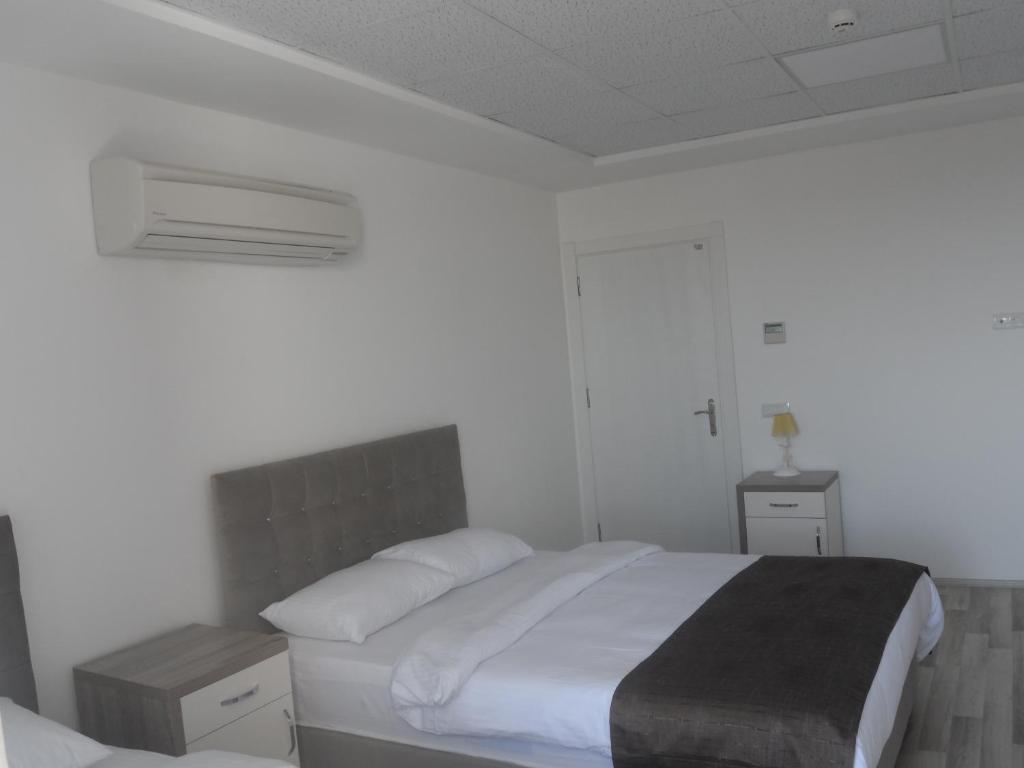 een witte slaapkamer met een bed en twee nachtkastjes bij Guckar Sehrinn Oteli in Serik