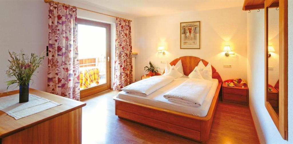 een slaapkamer met een groot bed en een raam bij Gasthof Weisses Kreuz in Naturno