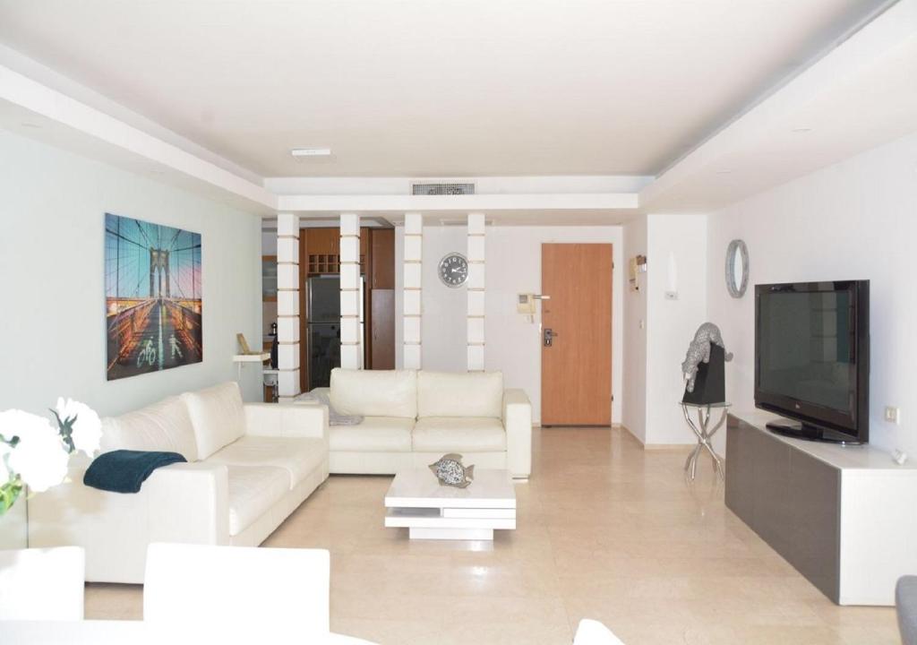 un soggiorno con mobili bianchi e TV a schermo piatto di Sweethome26 Luxury Apartment Eilat / Free Parking a Eilat