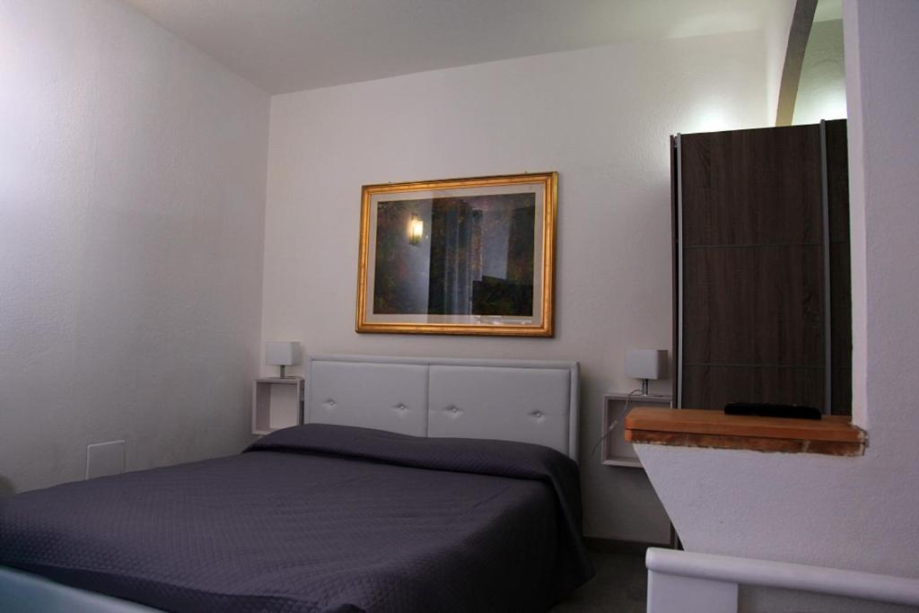 1 dormitorio con 1 cama y una foto en la pared en Affittacamere Gallurà, en Calangianus
