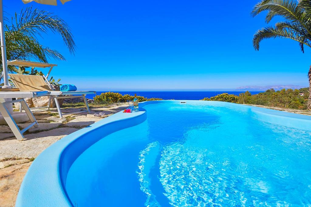 a blue swimming pool with a view of the ocean at Villa Gabbiano - Scopello-Villas in Scopello