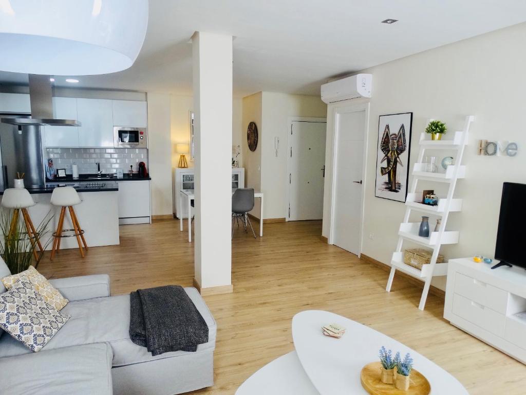 sala de estar con sofá blanco y cocina en Apartamento El Barranco, en Sevilla