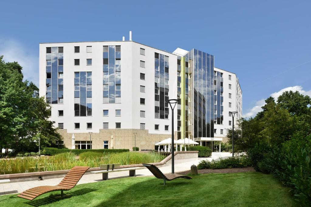 zwei Stühle auf einem Rasen vor einem Gebäude in der Unterkunft NOVINA HOTEL Südwestpark in Nürnberg