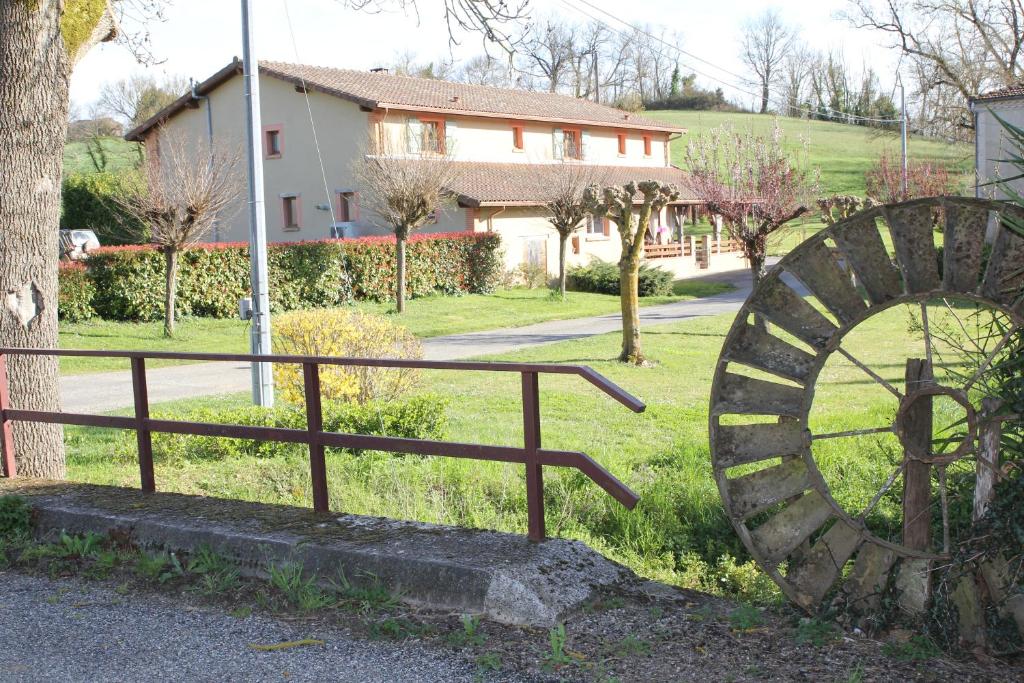 a large wooden wheel sitting next to a fence at Chambre d'Hôtes Le Moulin d'Encor in Seysses-Savès