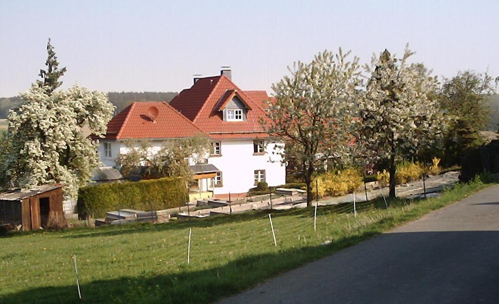 a white house with a red roof in a field at Willekes Blütenhof in Madfeld