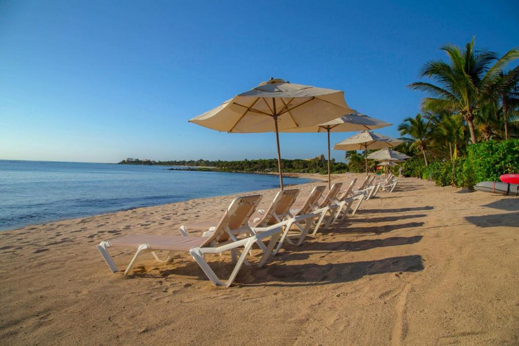 a row of chairs and umbrellas on a beach at Las Villas Akumal in Akumal