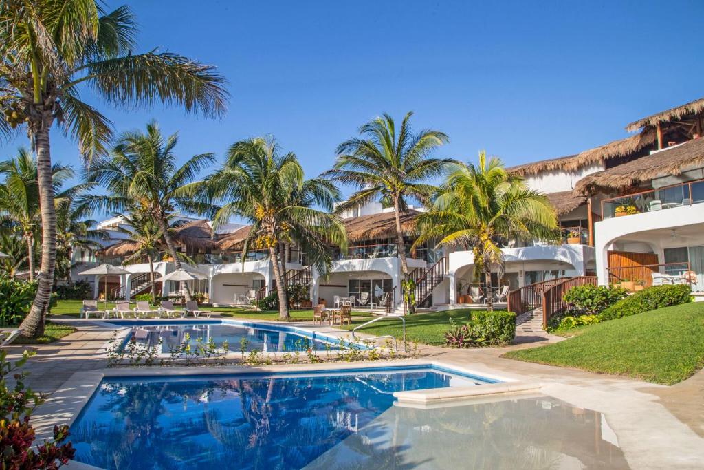 an exterior view of the resort with a swimming pool and palm trees at Las Villas Akumal in Akumal