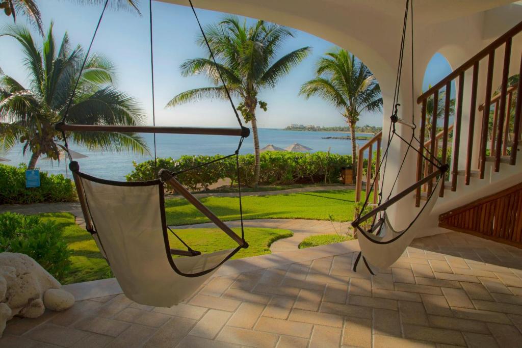 a porch with a hammock and a view of the ocean at Las Villas Akumal in Akumal