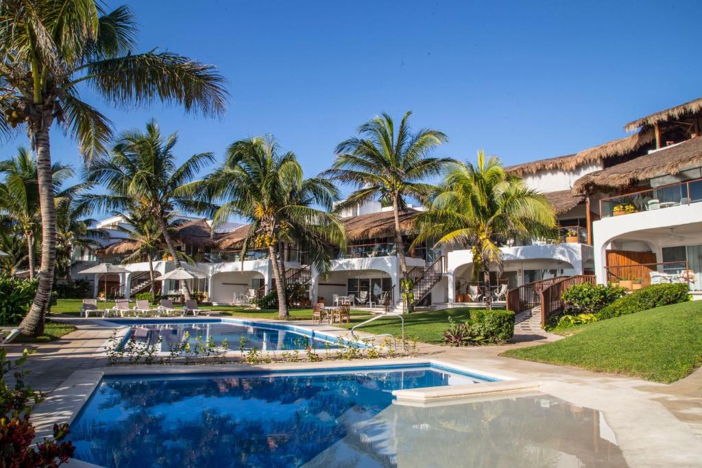 an exterior view of the resort with a swimming pool and palm trees at Las Villas Akumal in Akumal