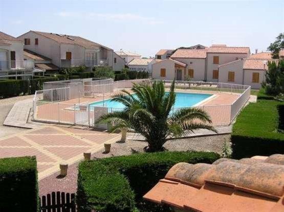 - une piscine avec un palmier et des maisons dans l'établissement Les Soleils de Pontaillac, à Vaux-sur-Mer