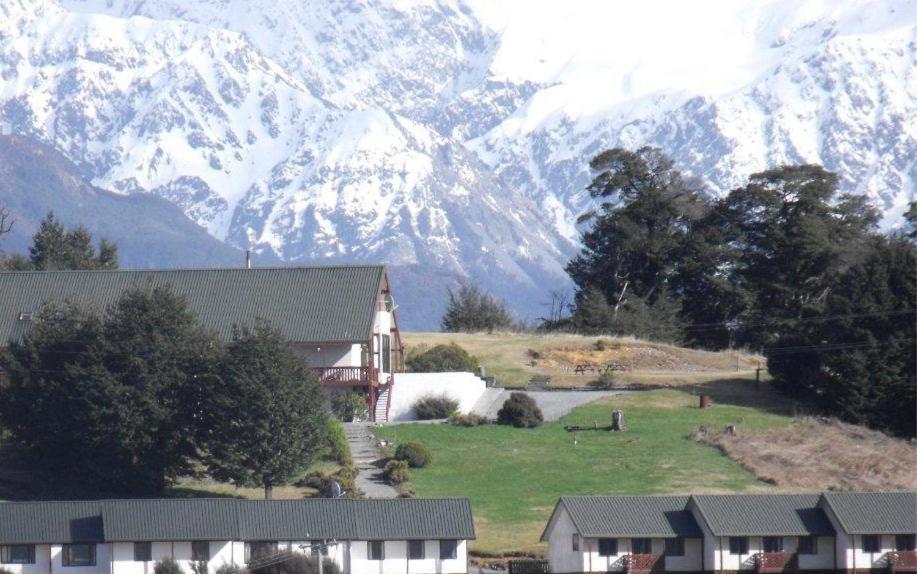 a house in a field with mountains in the background at The Bealey Hotel in Arthur's Pass