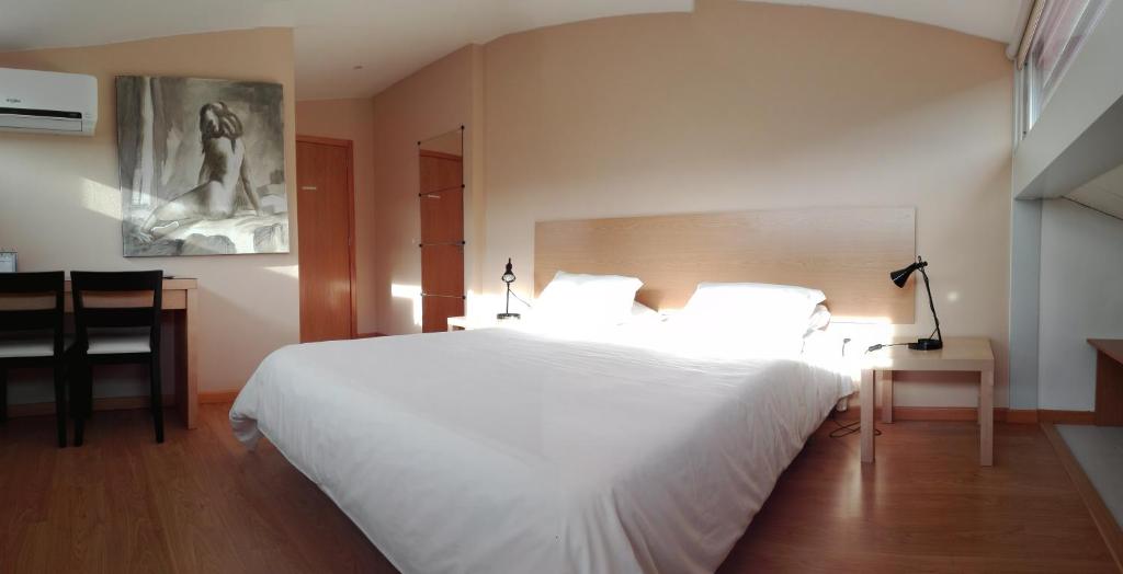 Un dormitorio con una gran cama blanca y una mesa. en Penthouse - Low Cost, en Vouzela