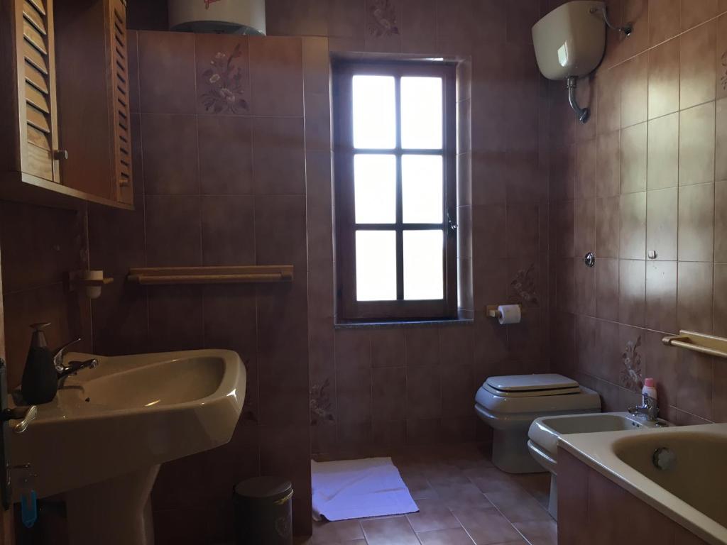 a bathroom with a sink and a toilet and a window at Mille Soli Bed and Breakfast in Buggerru