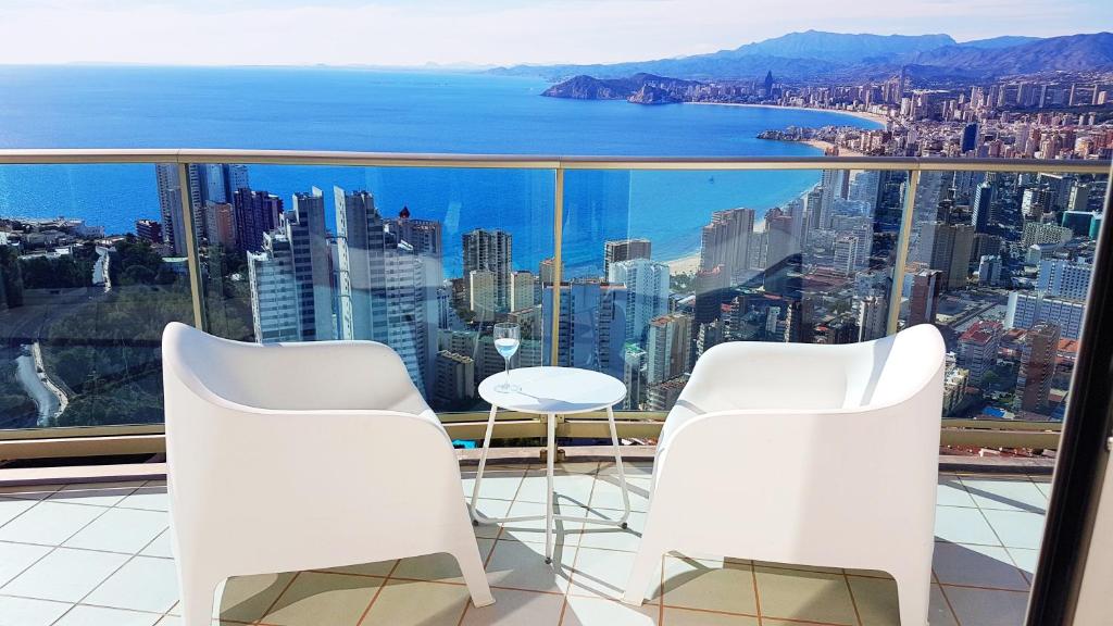 a balcony with white chairs and a view of the city at Luxury apartment on the 40th floor with amazing views in Benidorm