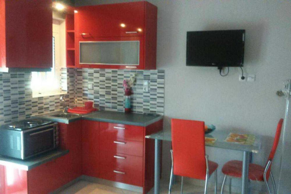 a kitchen with red cabinets and a table with red chairs at Βlue Horizon Lixouri in Lixouri