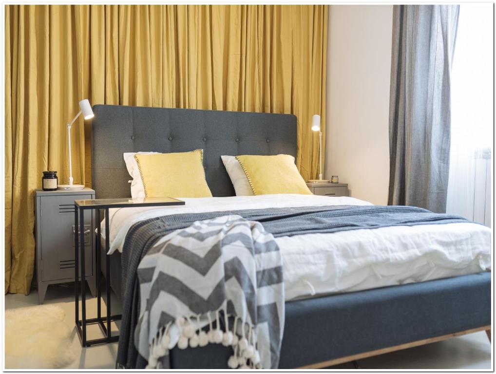 a bedroom with a large bed with yellow pillows at Old Town Studio - Panoramic City View in Bucharest