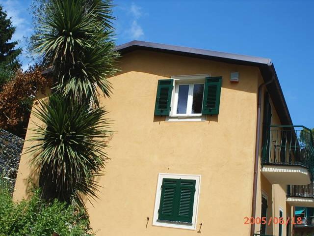 um edifício amarelo com persianas verdes e uma palmeira em The Palm House em Santa Margherita Ligure