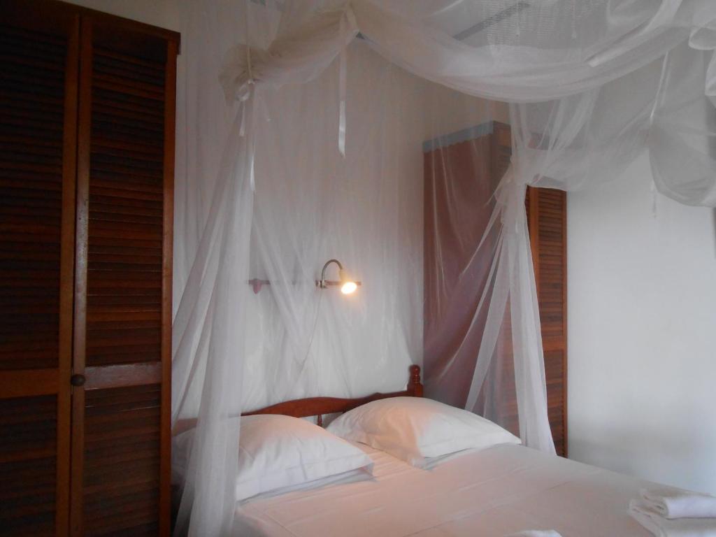 1 dormitorio con cama con dosel, sábanas y almohadas blancas en BEL Z 'IGUANE en Trois-Rivières
