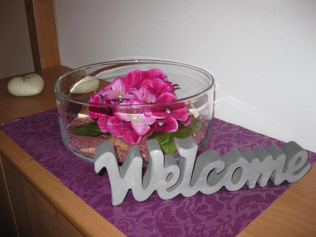 a glass bowl with flowers on a table with the word welcome at Ferienwohnung Langenselbold in Langenselbold