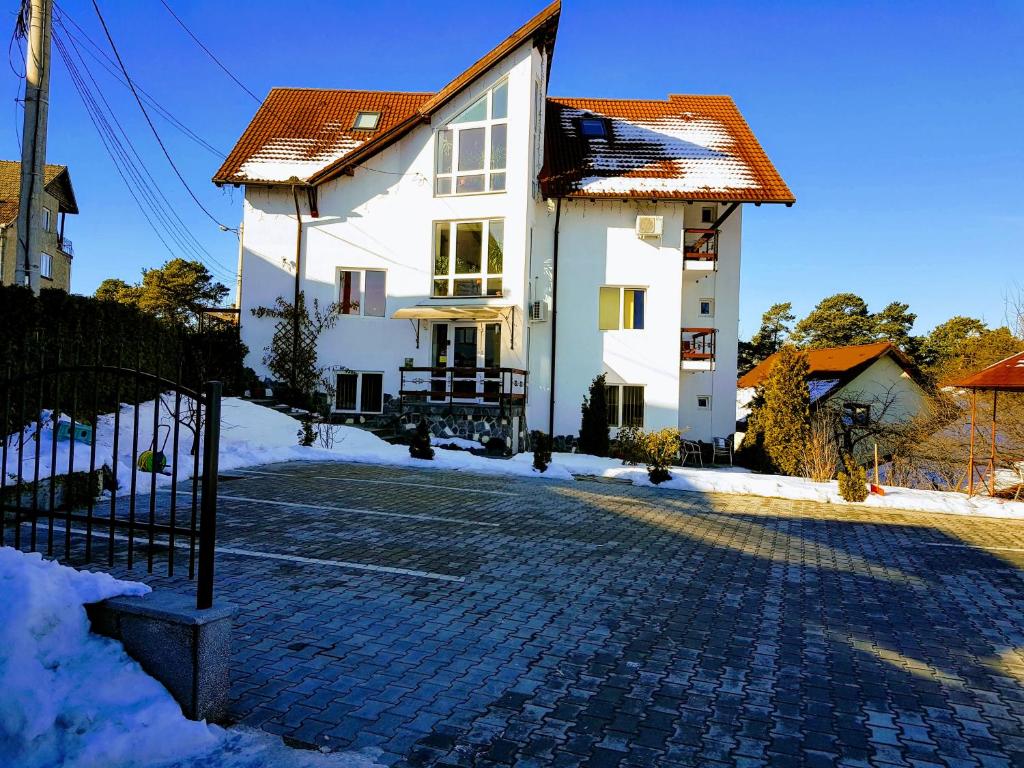 ein weißes Haus in einer Kopfsteinpflasterstraße in der Unterkunft Pensiunea Riunione in Braşov