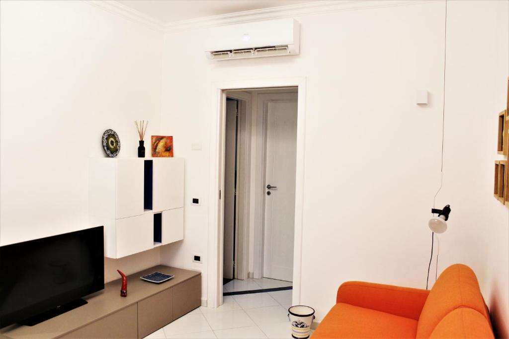 a living room with an orange couch and a tv at MD House - Amalfi Coast in Maiori