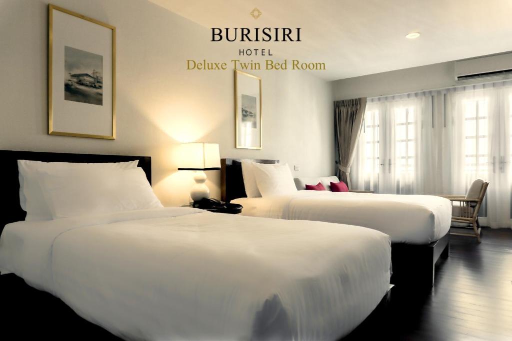 two beds in a hotel room with a sign on the wall at Buri Siri Boutique Hotel in Chiang Mai