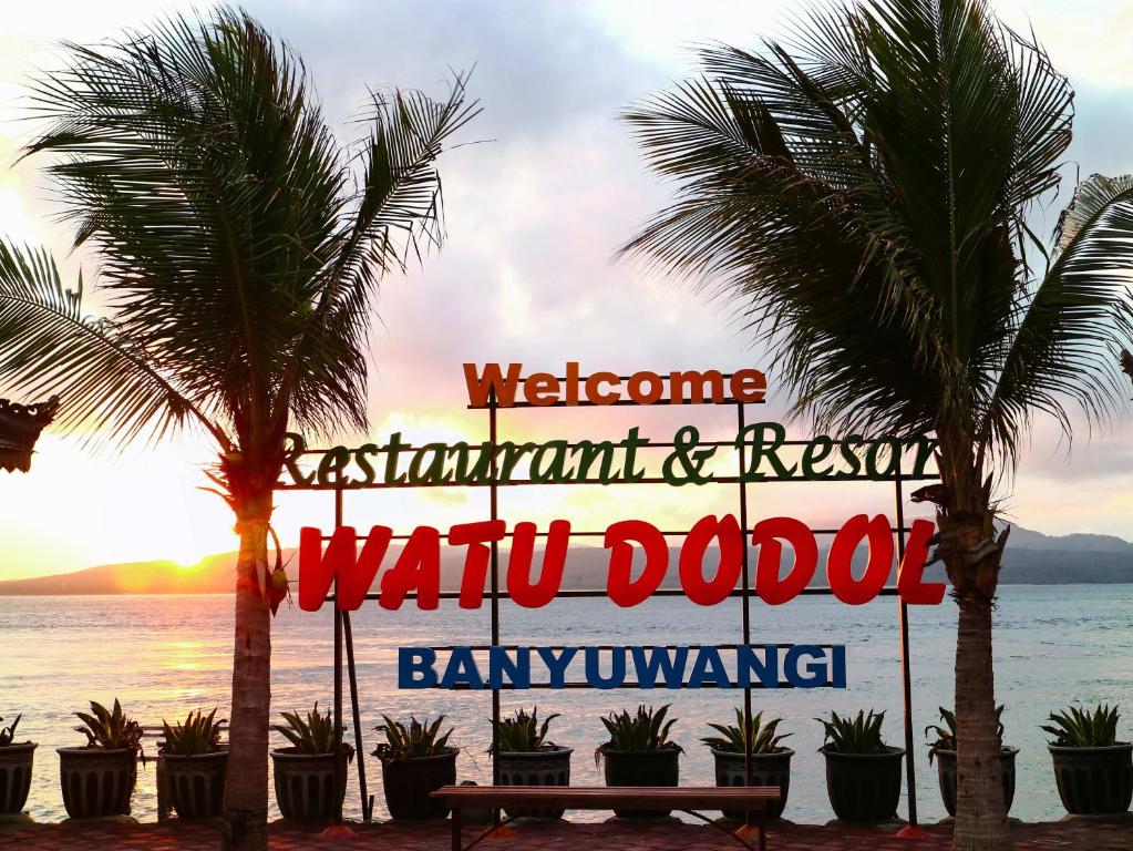 a welcome sign at the beach with palm trees at Watu Dodol Hotel & Restaurant in Banyuwangi