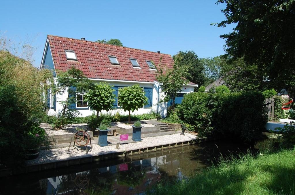 una casa con un río delante de ella en B&B Marialin, en Wijdewormer