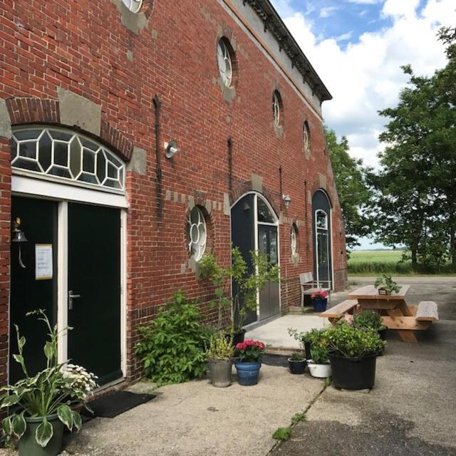 a brick building with plants and a picnic table in front of it at Theaterwerkplaats private appartment in Kantens