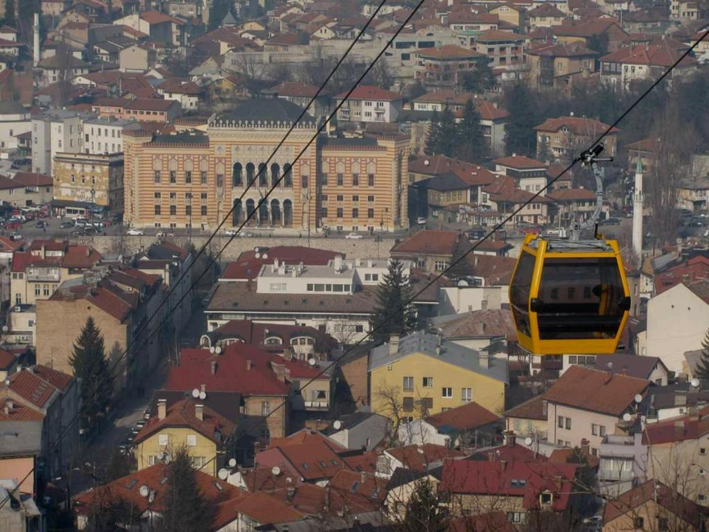 un teleférico amarillo volando sobre una ciudad en Cozy Apartment in heart of Sarajevo en Sarajevo