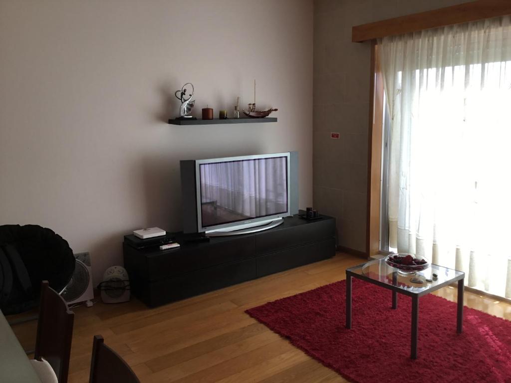 a living room with a flat screen tv and a table at Apartamento Parque Urbano in Ponta Delgada