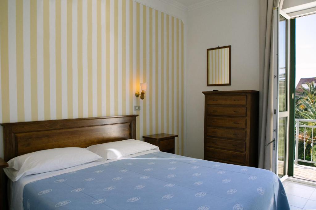 a bedroom with a blue bed and a window at Hotel Giardino in Follonica