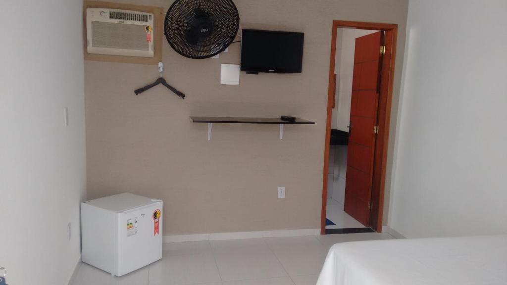 a room with a refrigerator and a clock on the wall at Pousada Portico de Buzios in Armacao dos Buzios