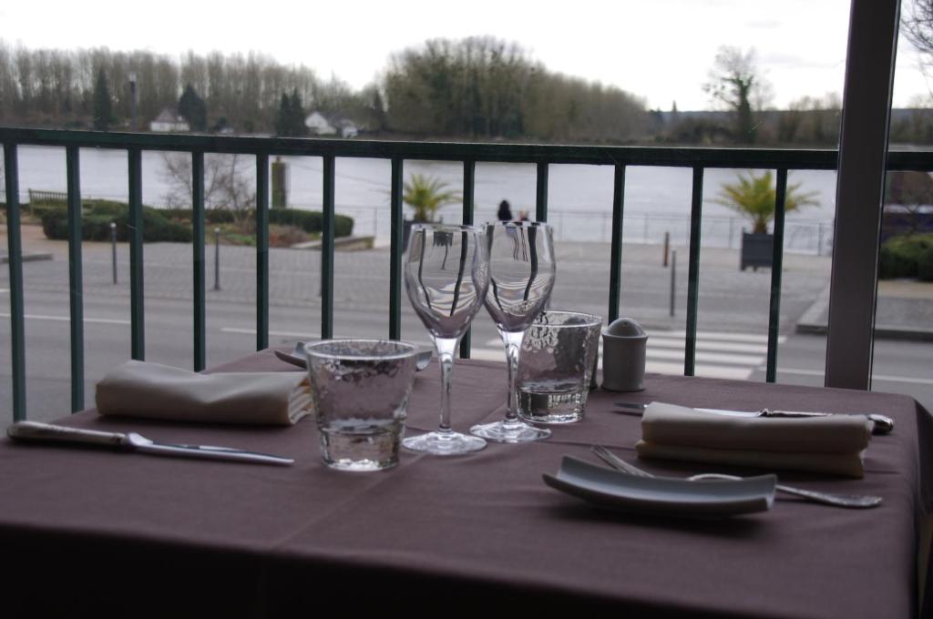 a table with wine glasses on a balcony at Logis Le Normandie in Caudebec-en-Caux