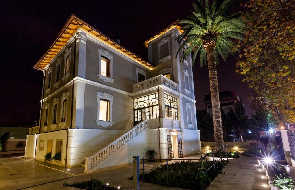 a large white house with a palm tree at night at Hotel 900 in Giulianova