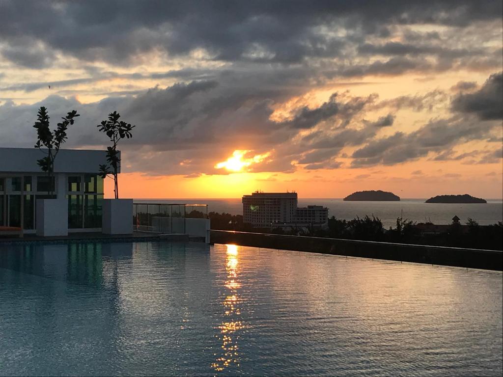 a sunset over a swimming pool at a resort at Sunset Seaview Vacation Condos @ Infinity Avenue in Kota Kinabalu